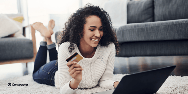 Woman laying on floor with a credit card and laptop