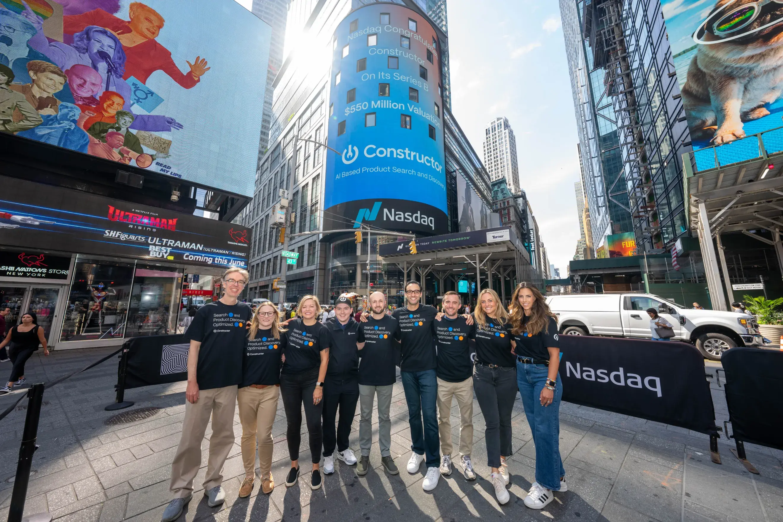 The Constructor leadership team standing in front of a Constructor advertisement 