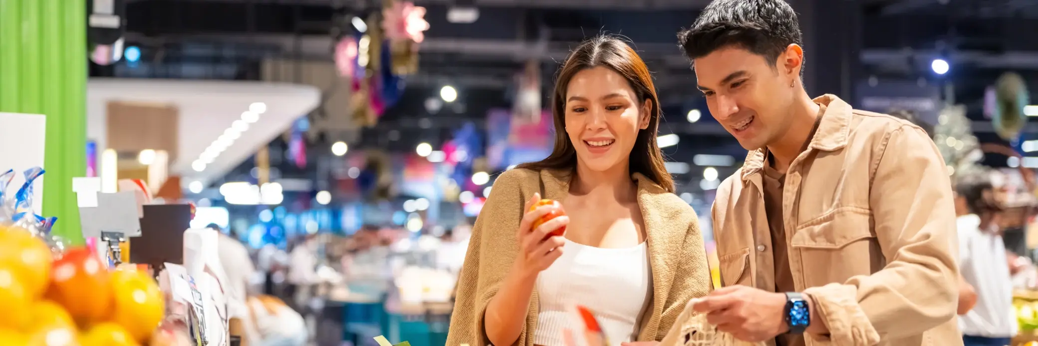 two people looking at fruits in a grocery store
